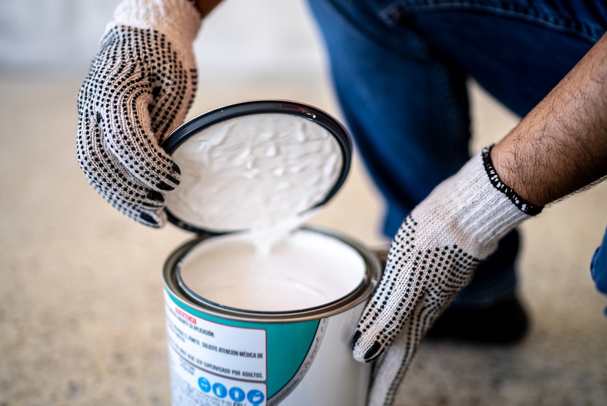 Person opening a can of white paint.