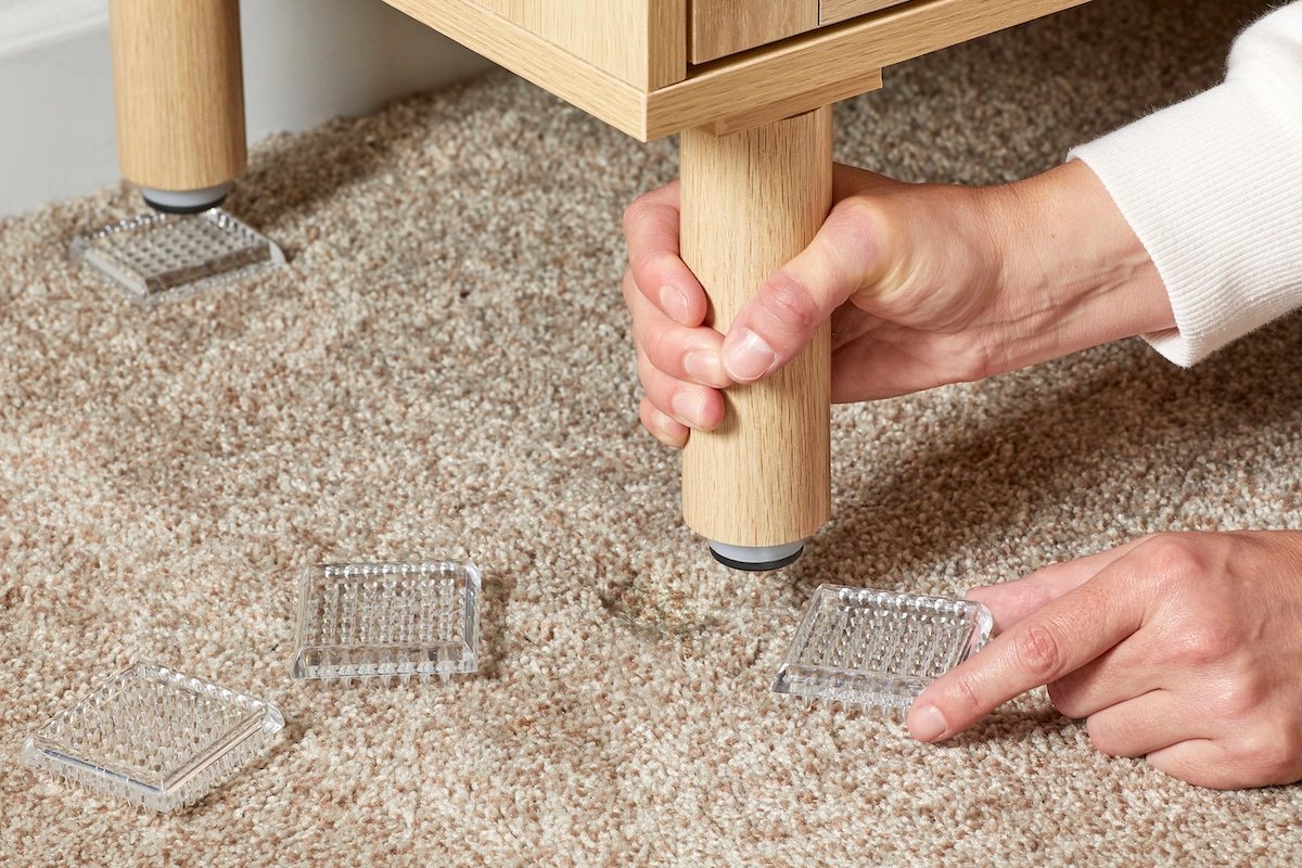Person uses carpet protectors to put under a table to prevent dents in carpet.