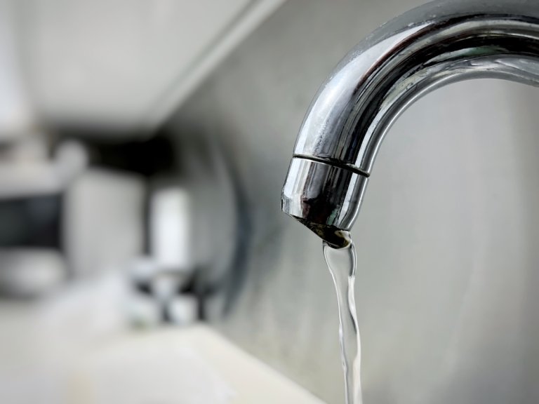 Close-up of kitchen tap with water flowing out of tap.