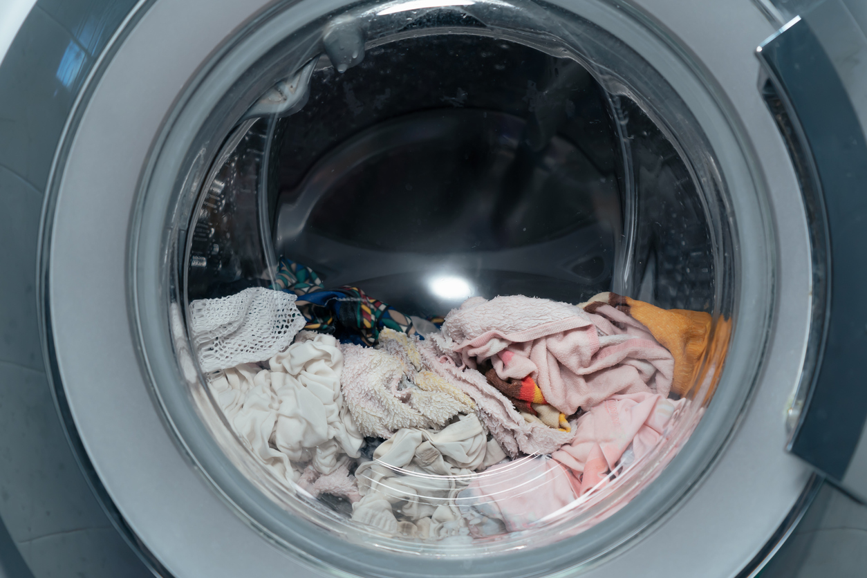 A front-loader washing machine is filled with wet clothes.