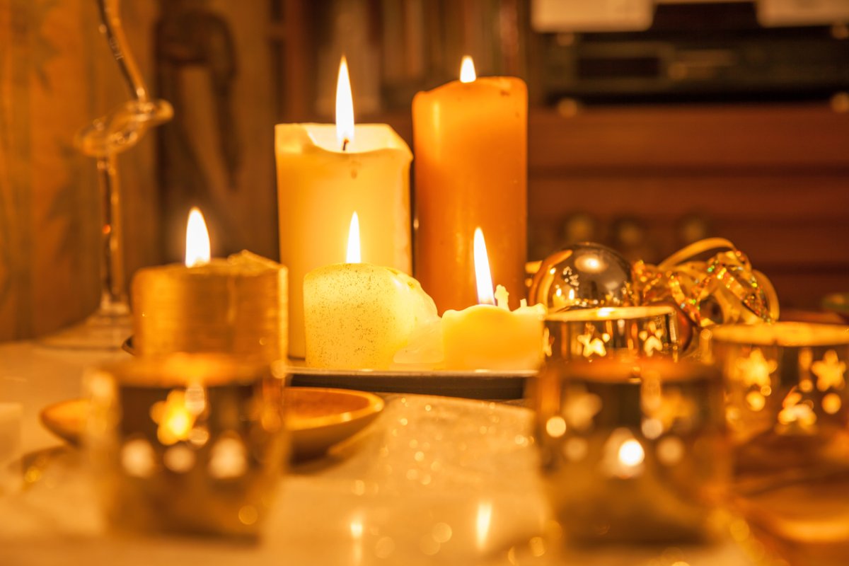 Many lit canldes on a table in a dim room, casting a golden glow.