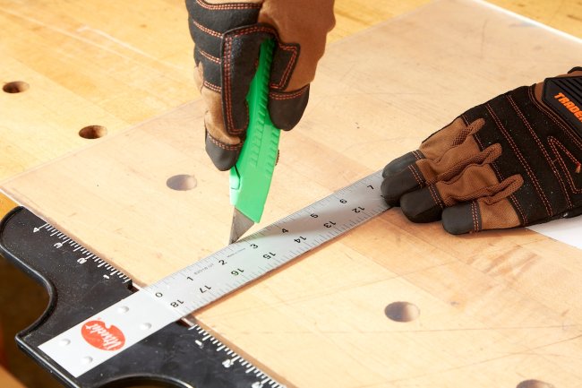 Person using green knife and ruler.