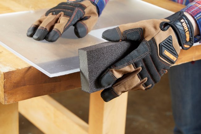 Person using grit sandpaper on plexiglass.