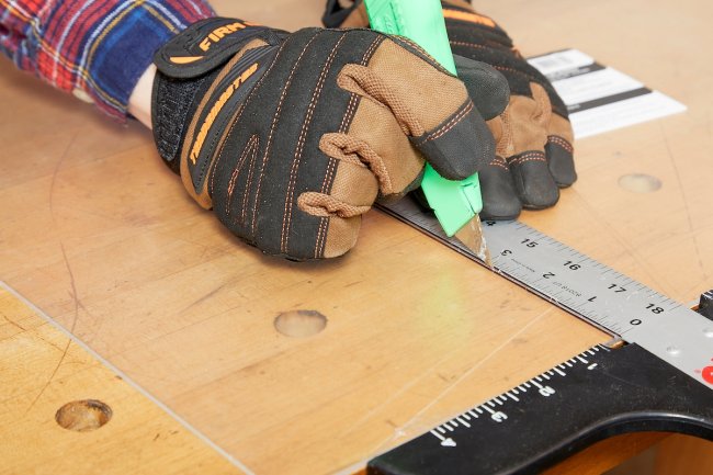 Person using knife to score thin plexiglass.