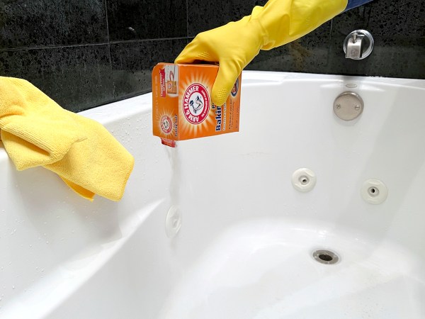 Woman using box of baking soda to clean a jetted tub.