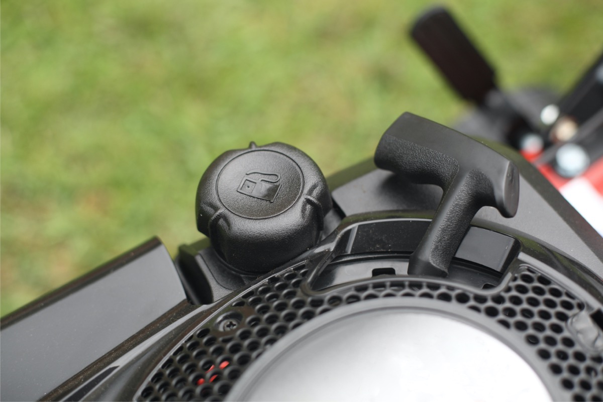 A black fuel cap is screwed onto a lawn mower.