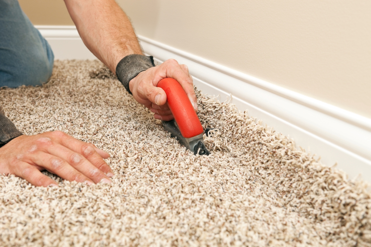 Person using carpet cutting knife on carpet.
