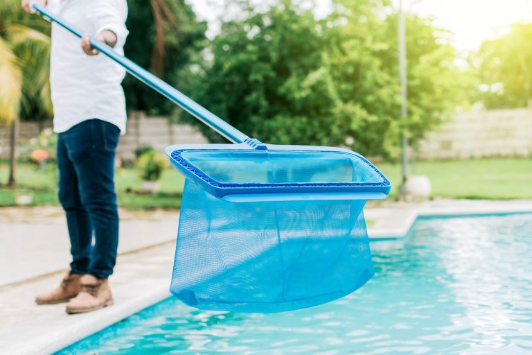 Man cleaning the pool with the Skimmer,