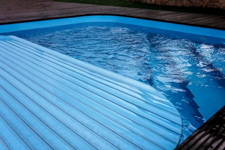 Automatic swimming pool covering system, over a pool.