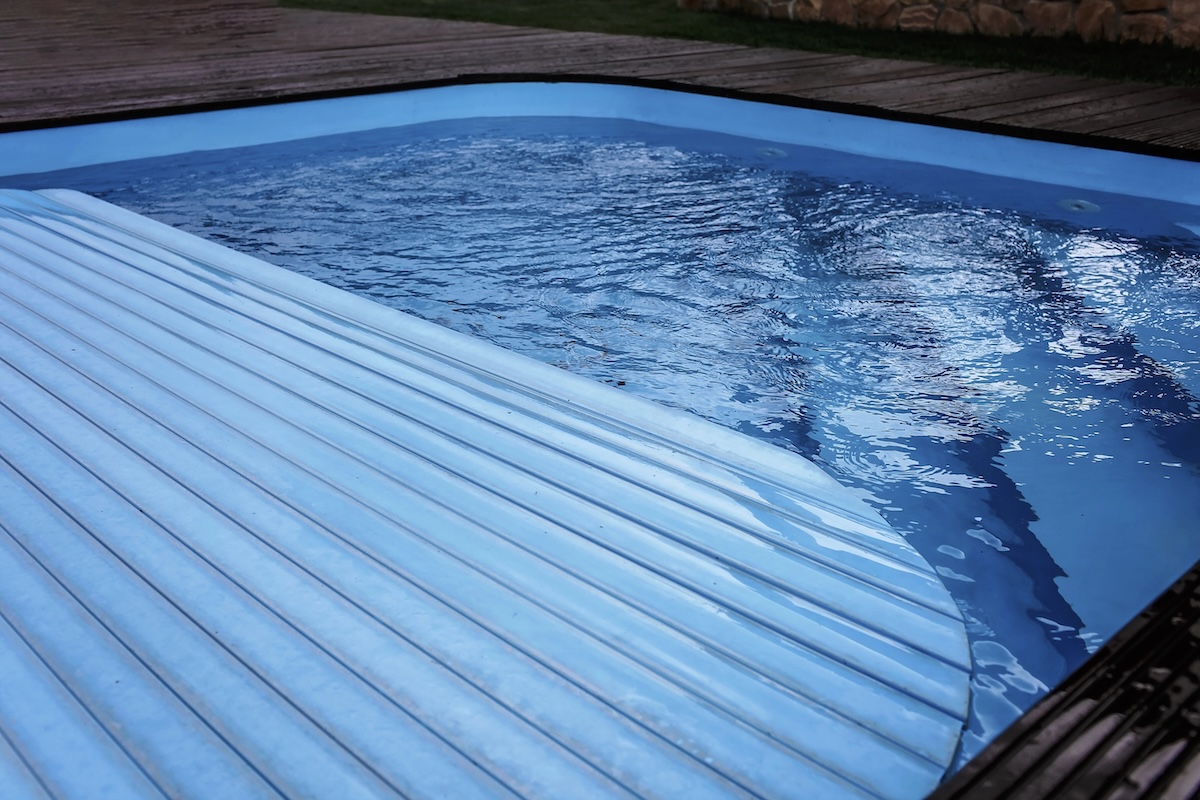 Automatic swimming pool covering system, over a pool.