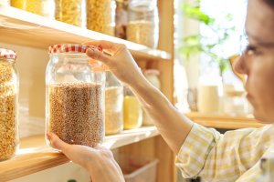 Woman inspecting dry goods in jar.