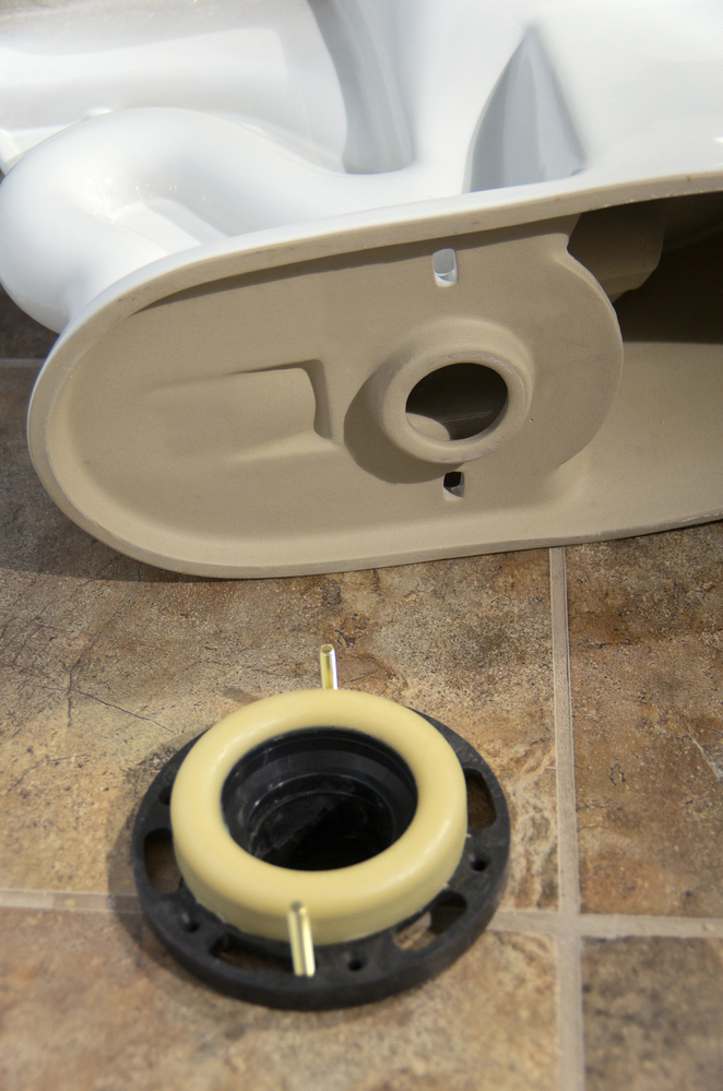Wax seal ring with toilet plumbing on tiled floors.