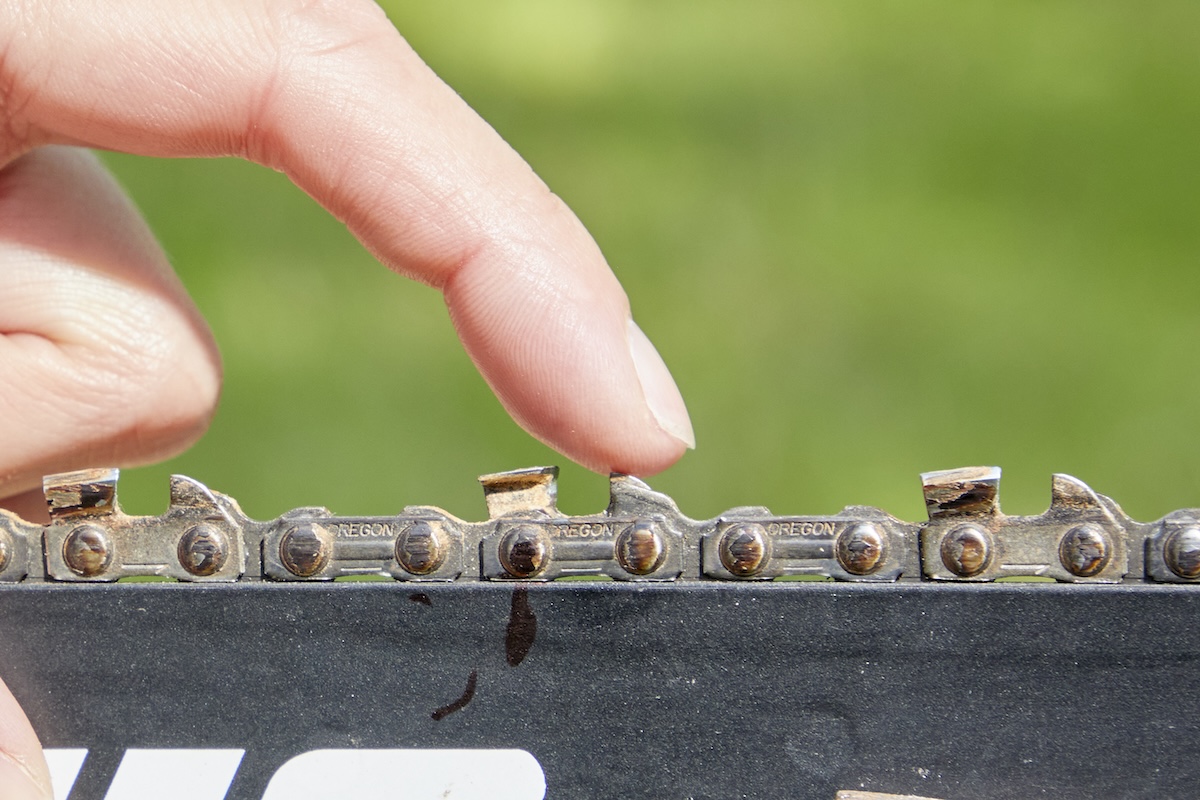 Using fingertips to check the depth gauges on a chainsaw chain.