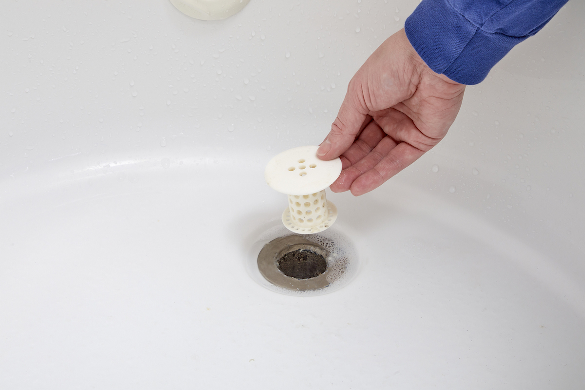 Woman replaces stopper in tub drain.