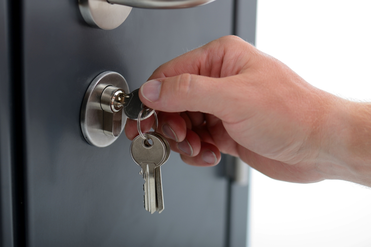 Person holding keys stuck in door lock.