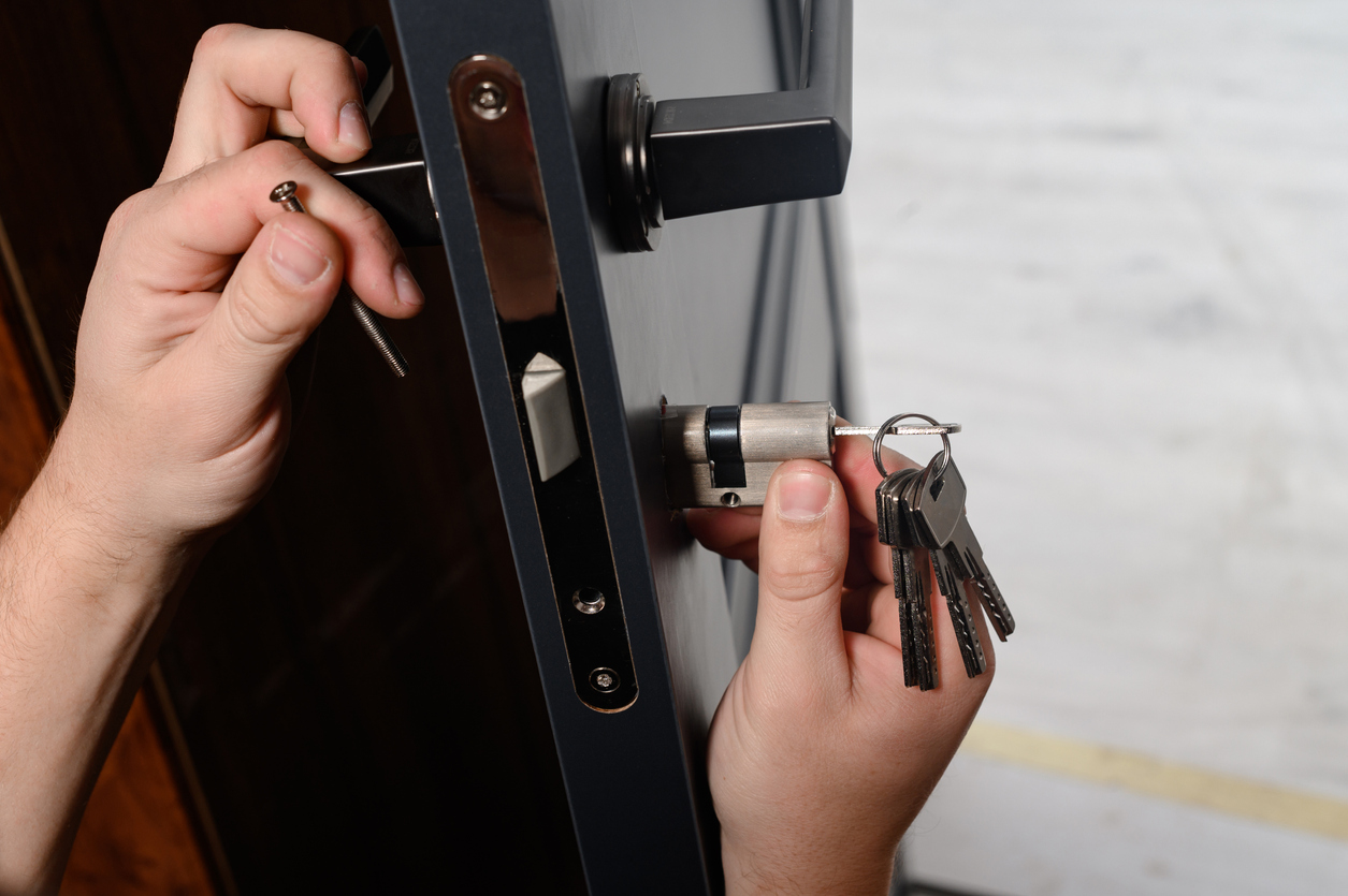 Locksmith installing core of lock into a door.