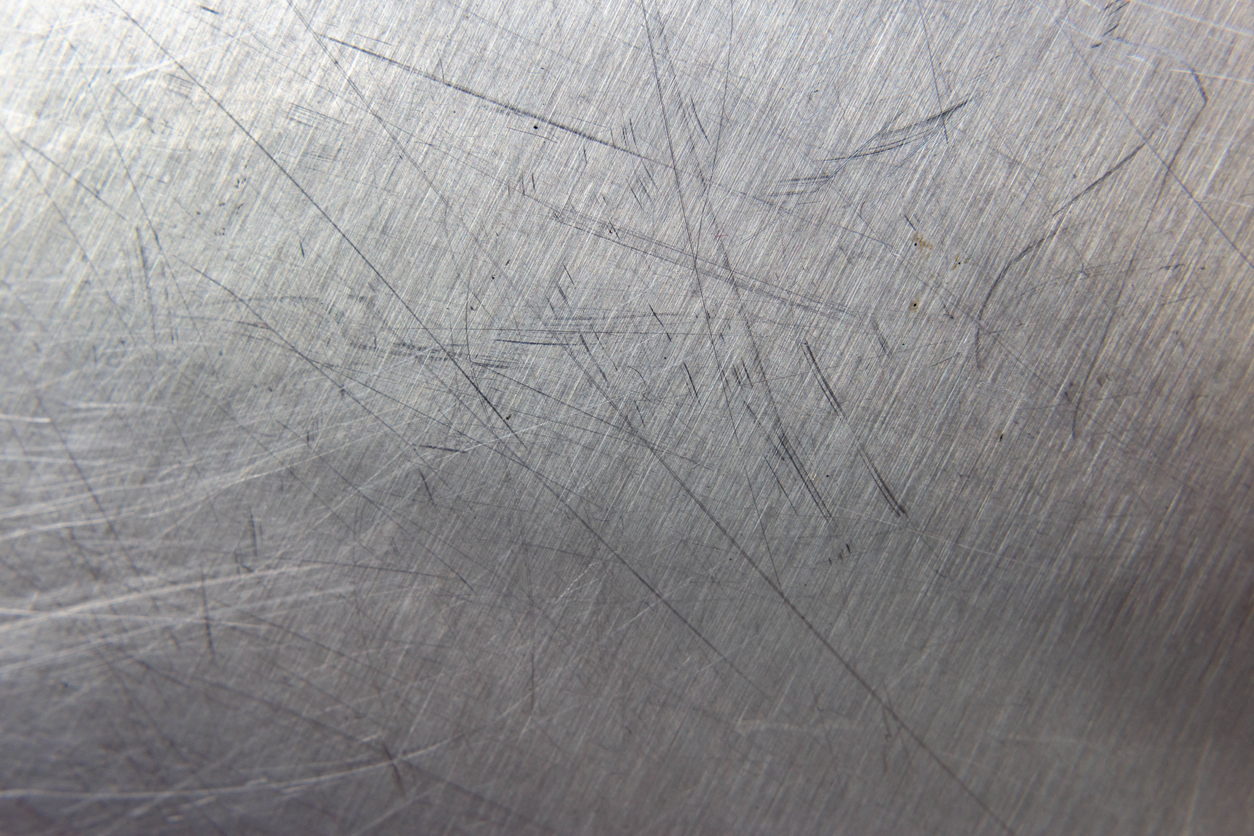 Close up of stainless steel countertop with several large scratches.