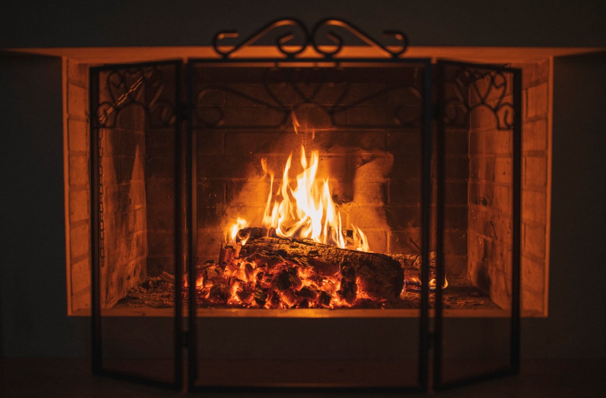 blazing, cozy fireplace behind fireplace screen in darkened room