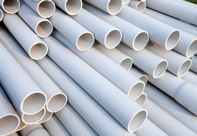 Several white PVC pipes stacked in a pile.