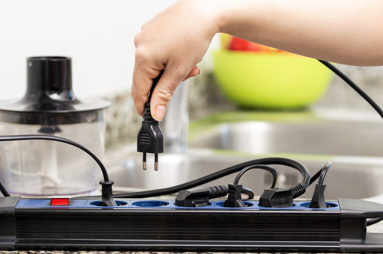 Woman's hand unplugging cord from a power strip in the kitchen