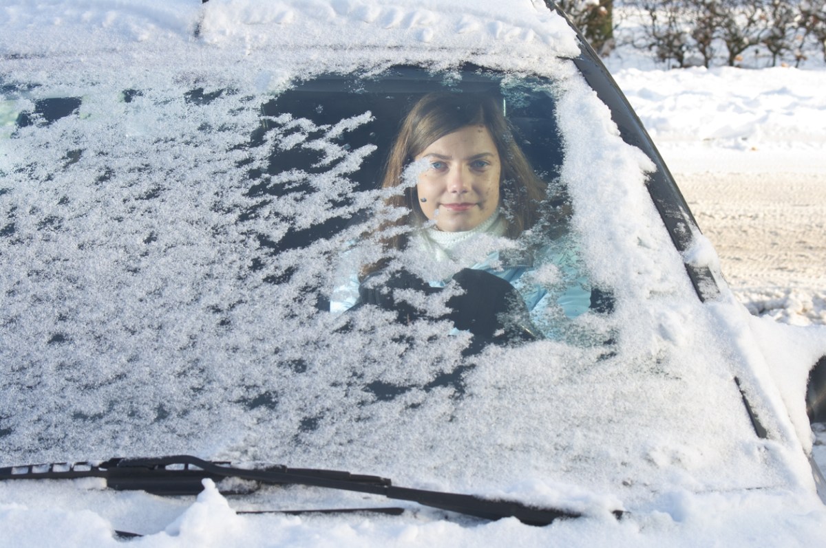 young woman in car behind frozen windshield
