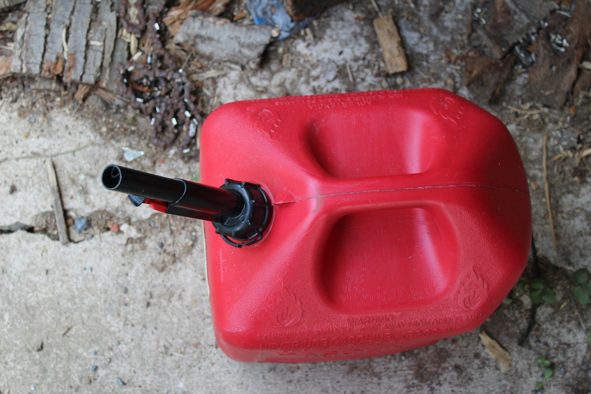 Bird's eye view of a red gas can on a dirty concrete floor.