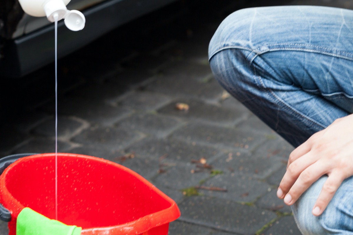 Person squirts soap into a red bucket.