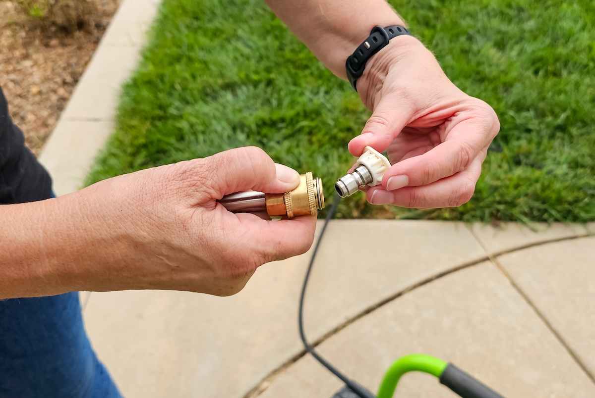 Man fits a nozzle on a pressure washer's wand.