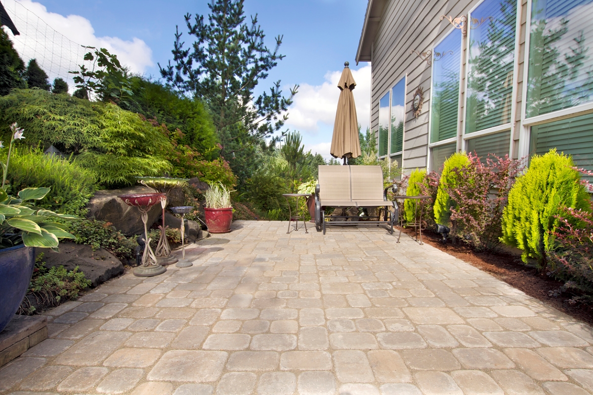 Side yard of house with vast hardscaped patio area.
