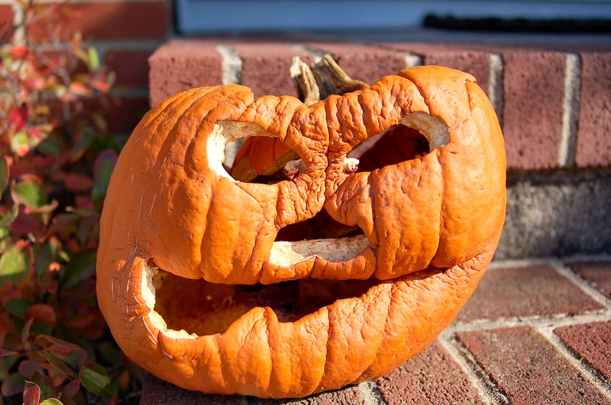 Rotting jack-o'-lantern on a brock porch.