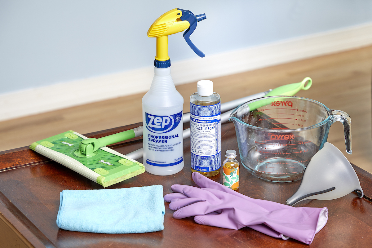 Materials needed to make homemade floor cleaner and apply it to hardwood floors, including spray bottle, mop, and castile soap.