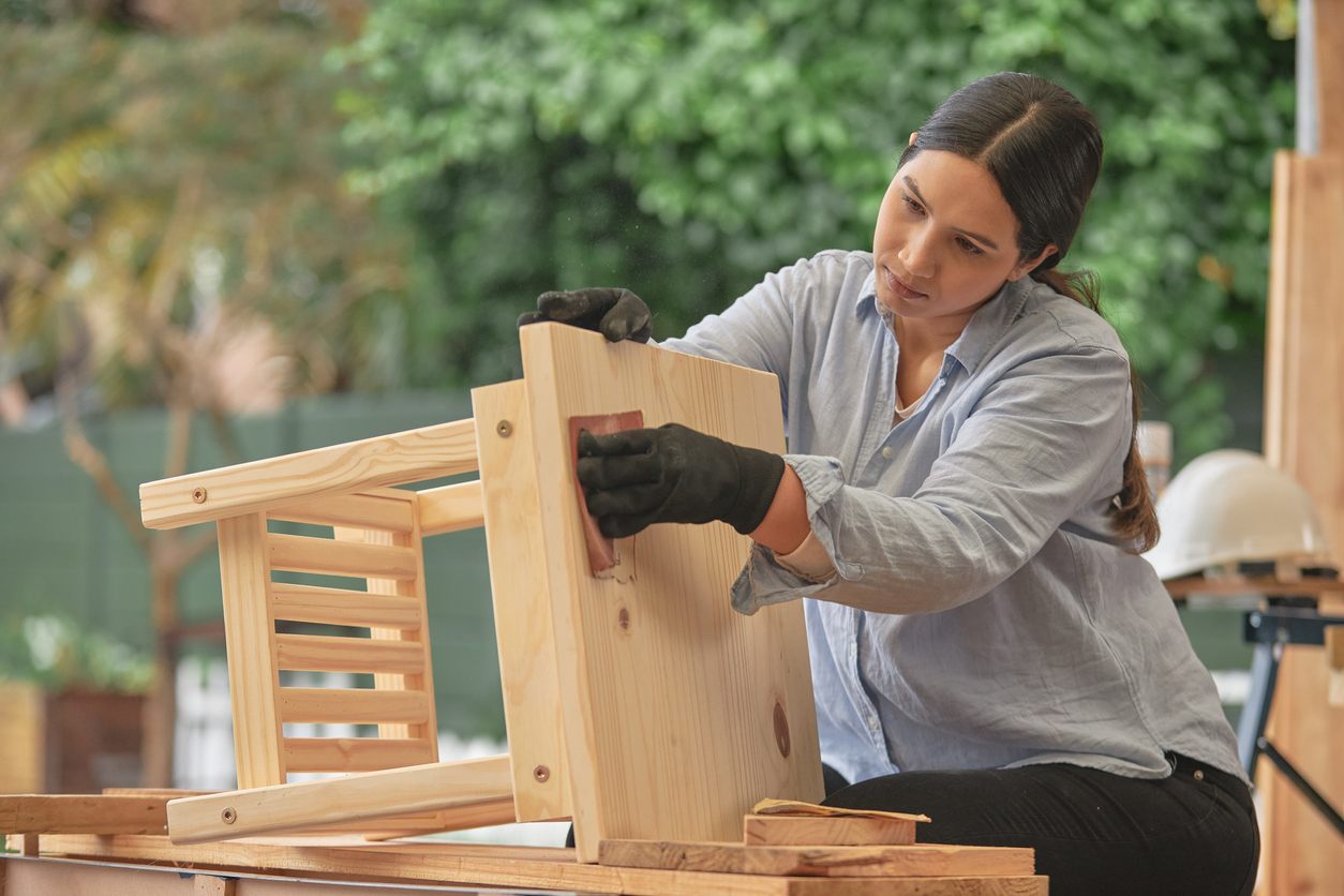 Female carpenter sanding a little wooden table in her workshop.