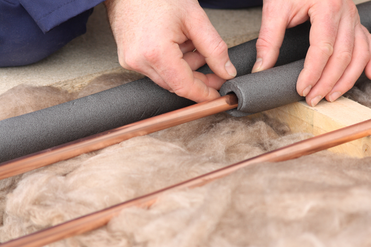 how to keep pipes from freezing close up hands insulating copper pipes