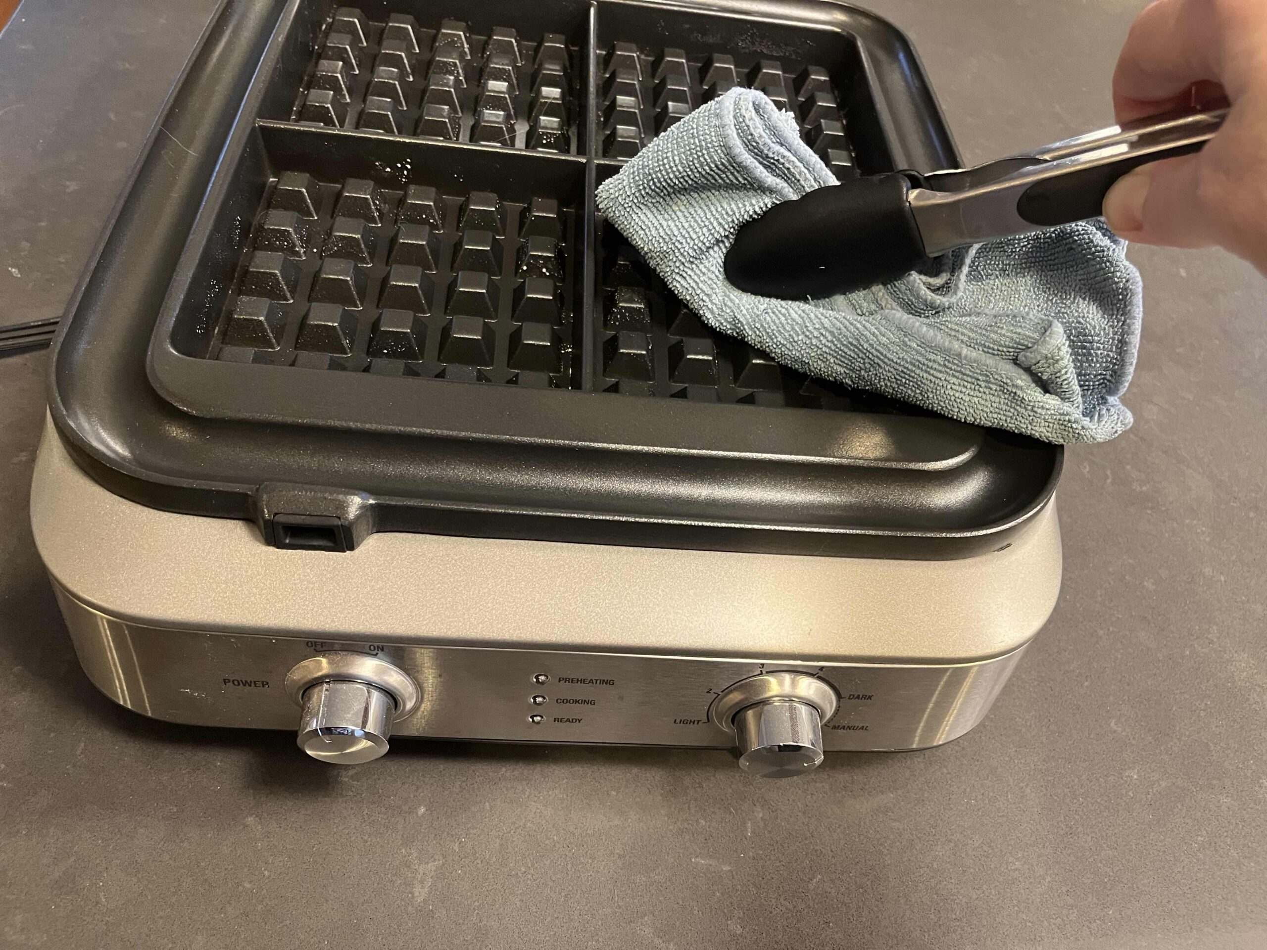 Cleaning Waffle Iron Plates with Cloth and Tongs