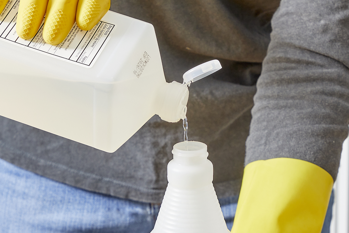 Woman pours rubbing alcohol into a spray bottle.