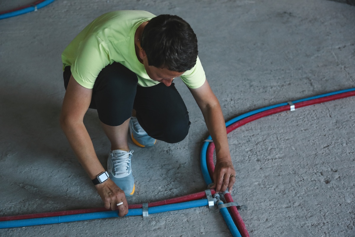 A woman works to install PEX pipes in a flooring project.