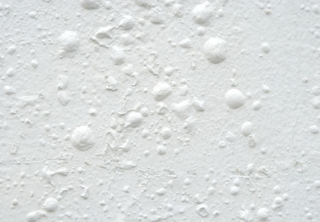 A white wall with bubbling paint.