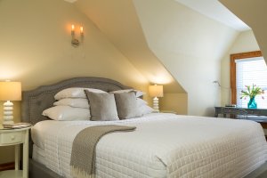 Bed and lamp in a modern interior with a dormer window, flooded with sunlight.