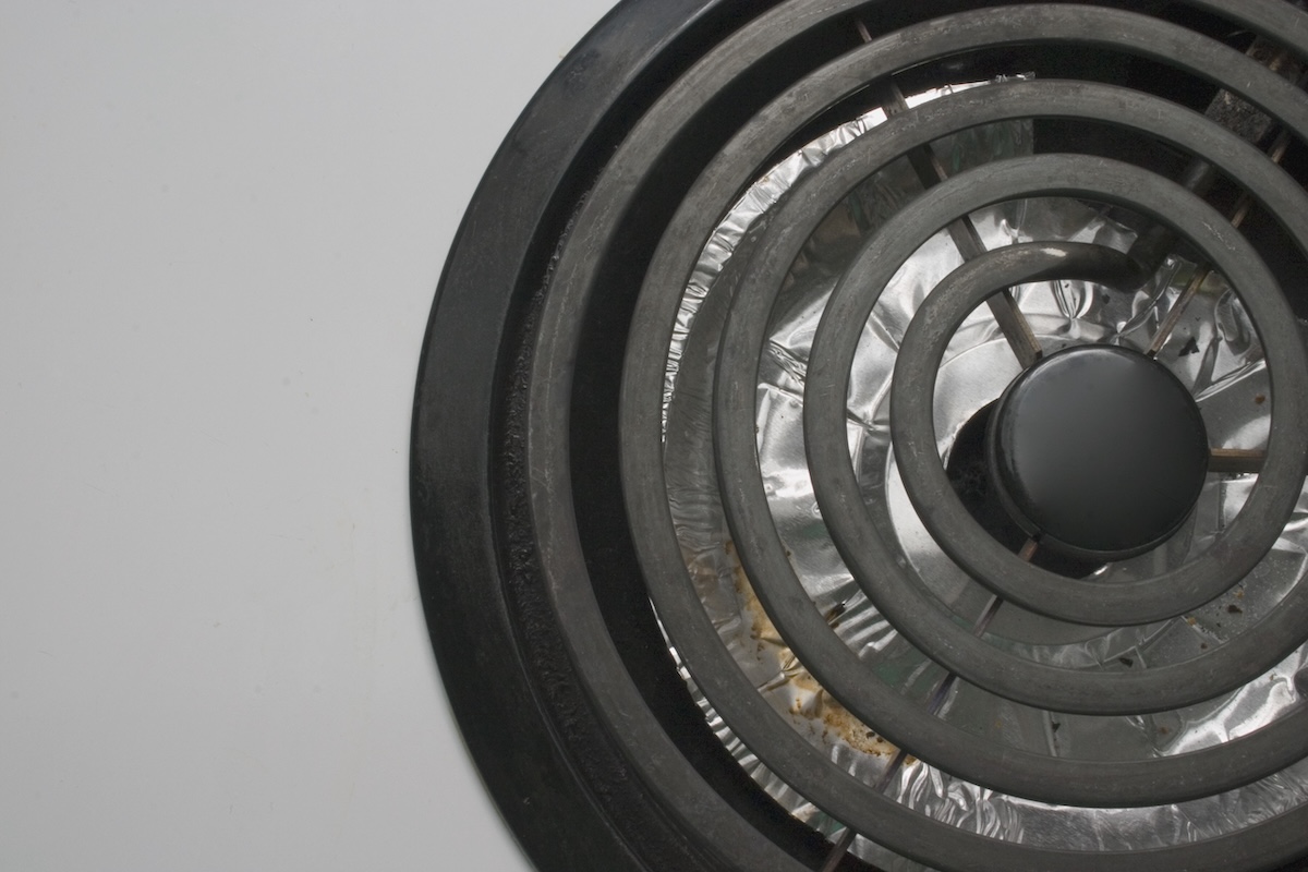 Close up of heating element and drip pan of an electric stove burner.