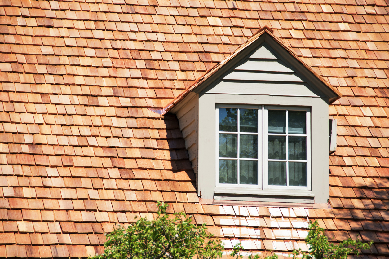 Dormer in roof of house with cedar shingles.