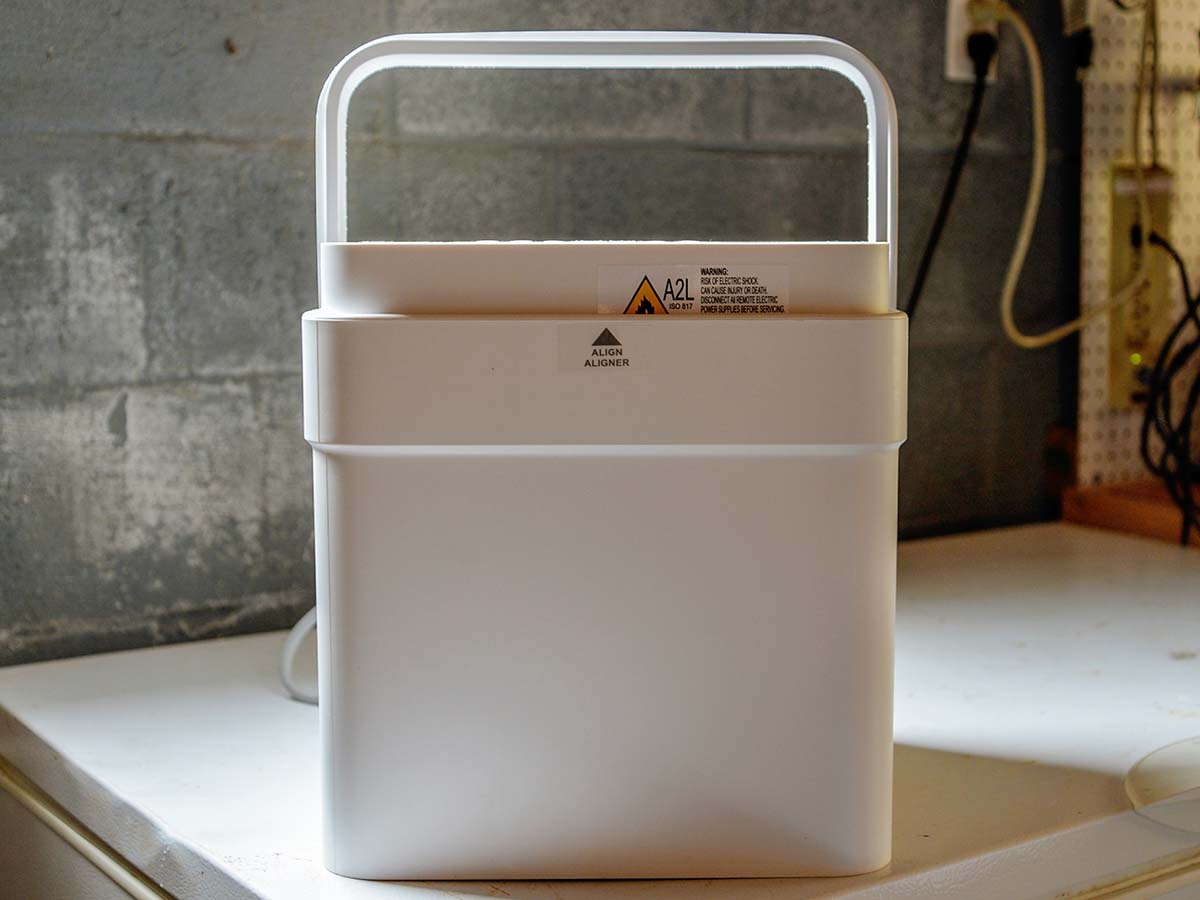 The Midea Cube 20-Pint Smart Control Dehumidifier on a worktable in a basement with cinder block walls.