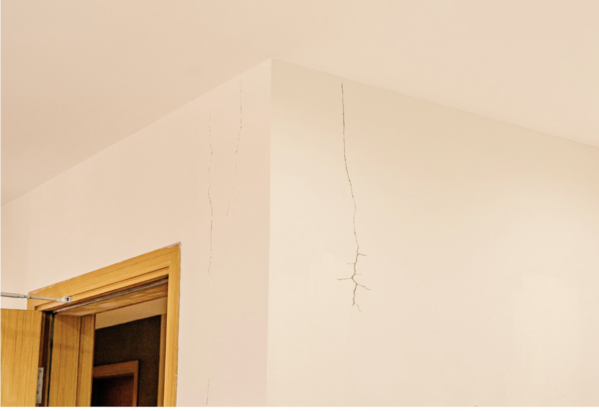 A vertical crack on an interior wall that spreads from the ceiling.