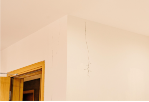 A vertical crack on an interior wall that spreads from the ceiling.