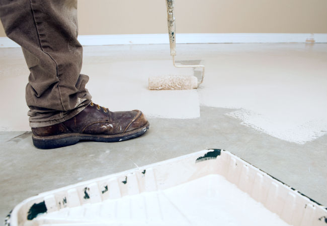 A painter rolling the best garage floor paint option onto a garage floor