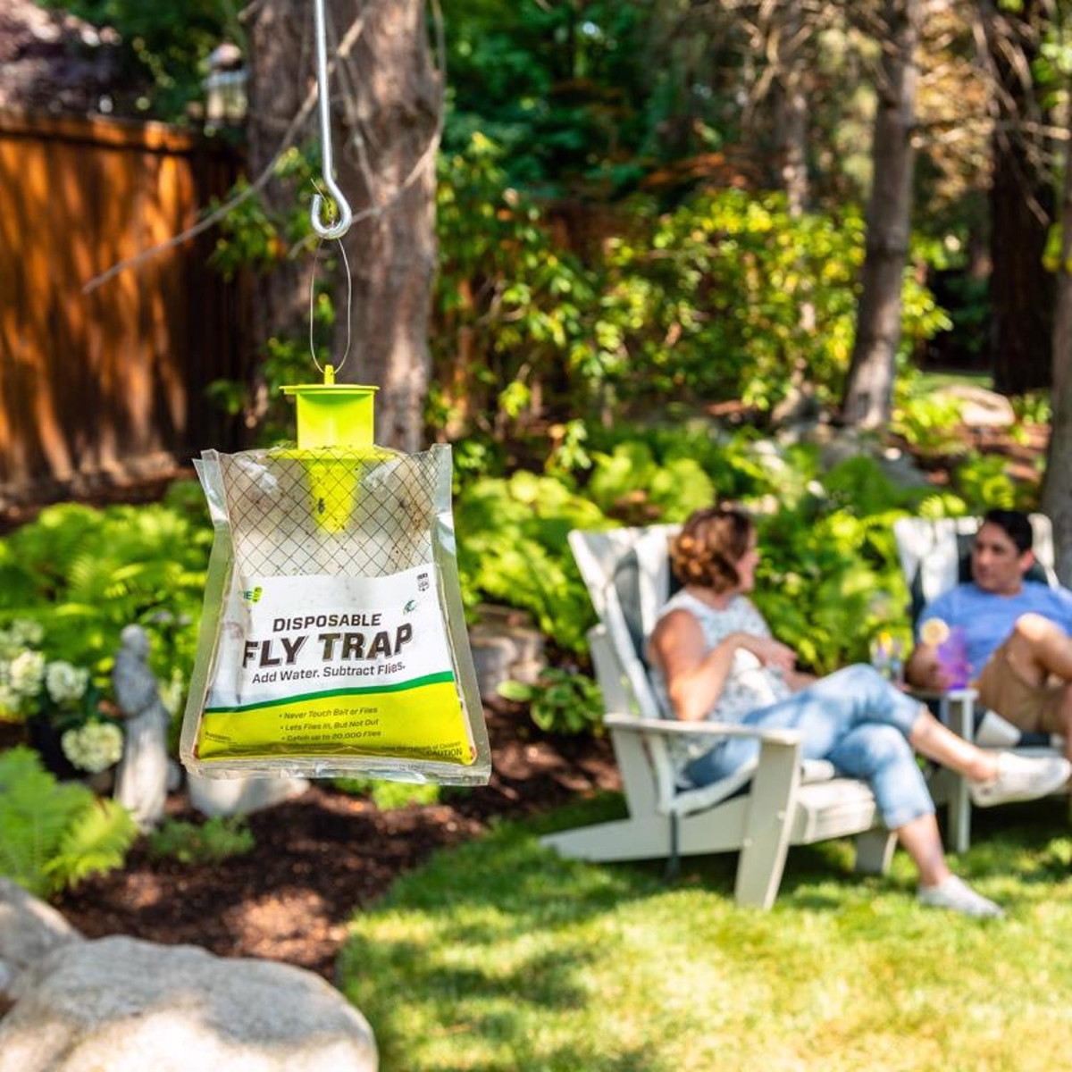 Outdoor fly trap hanging with people in lawn chairs in the background.