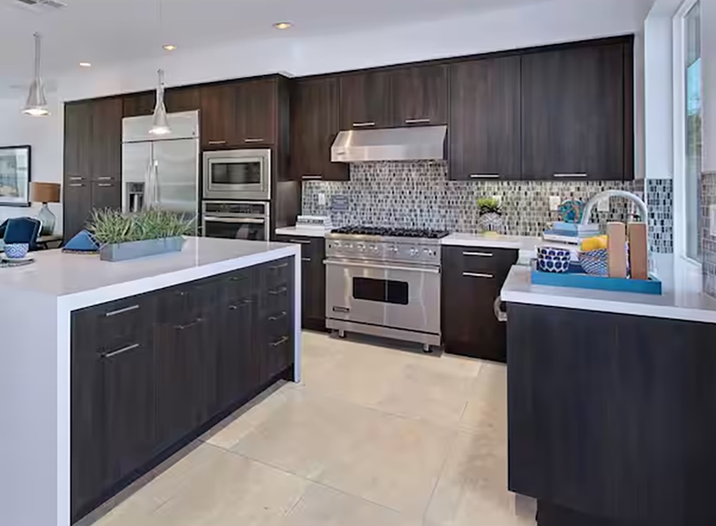Kitchen with dark espresso cabinetry and light colored stone tile floors.