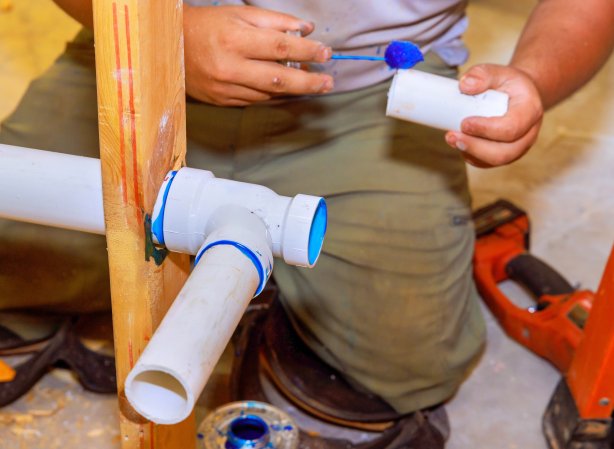Plumber glues plastic drainage PVC pipes system new house construction