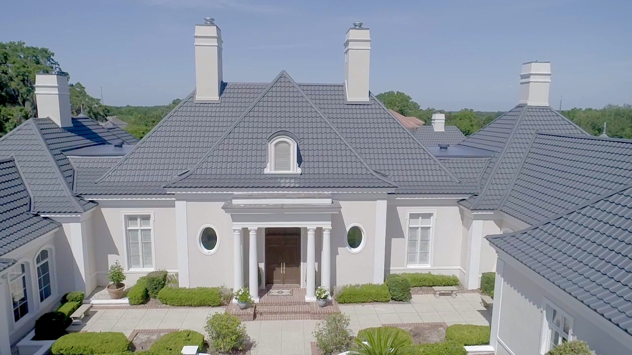 large luxury home with grey shingles on the roof.