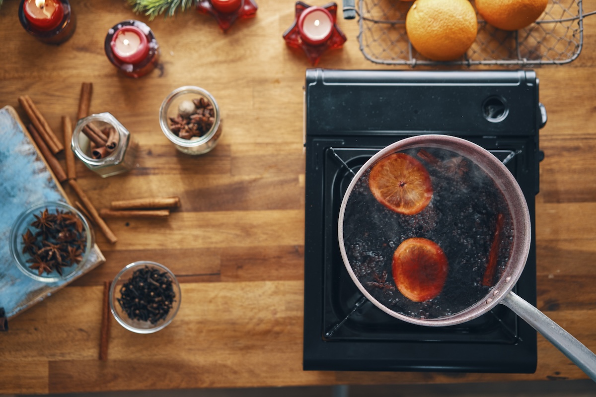 A pot of aromatics and fruit simmers on a hot plate.