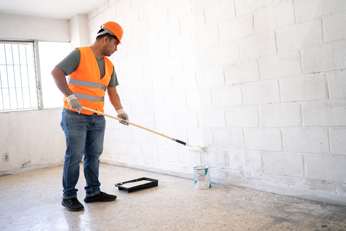 A contractor applying waterproofing paint to basement walls to prevent leaks.